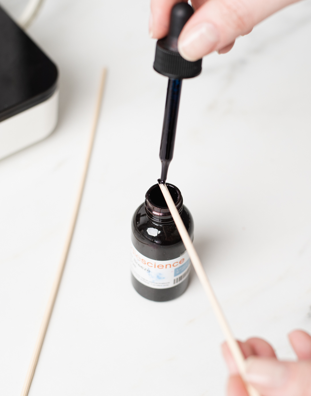 Putting liquid candle dye on a skewer.