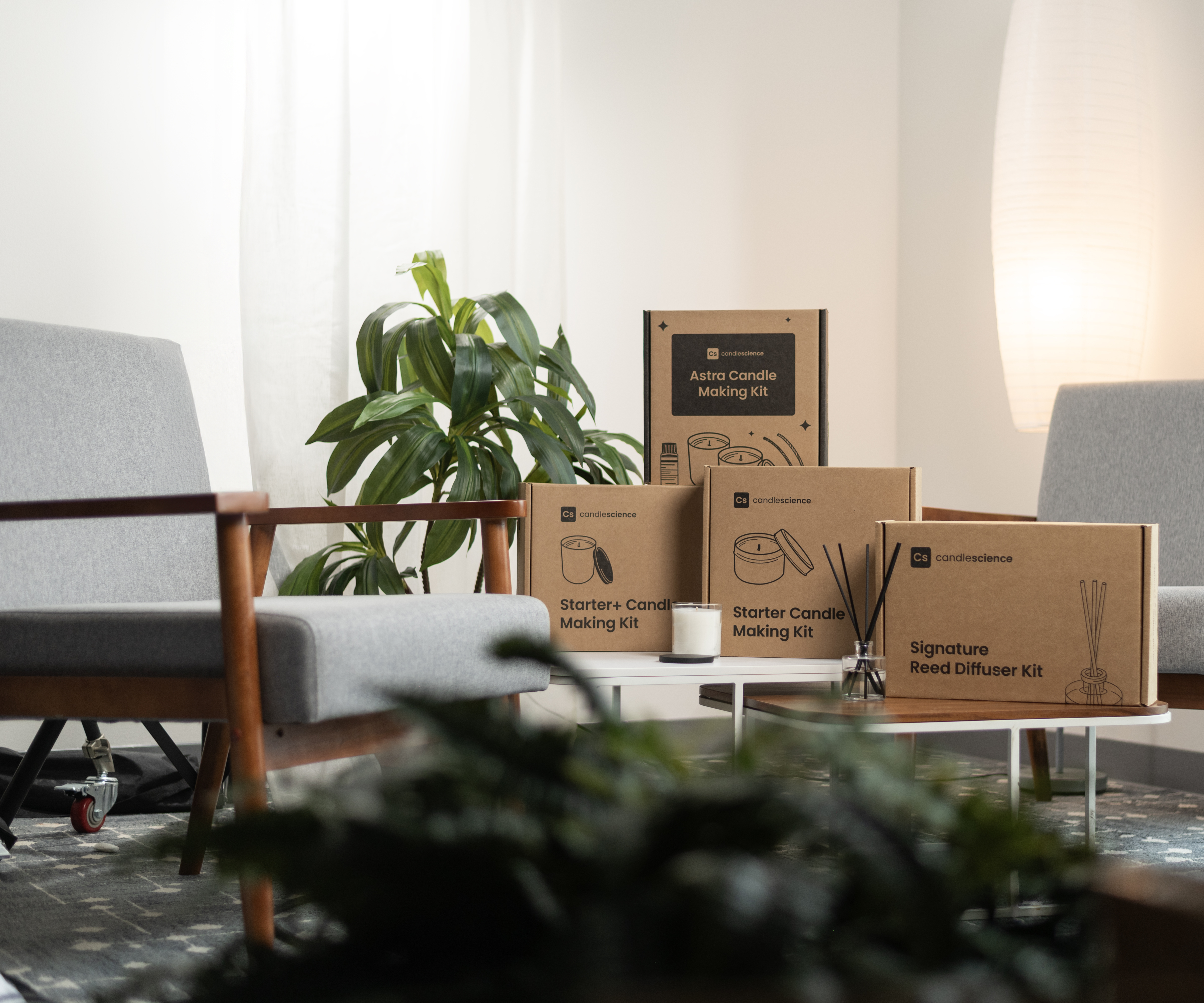 Candle making kits in brown boxes are stacked on a table in a living room setting