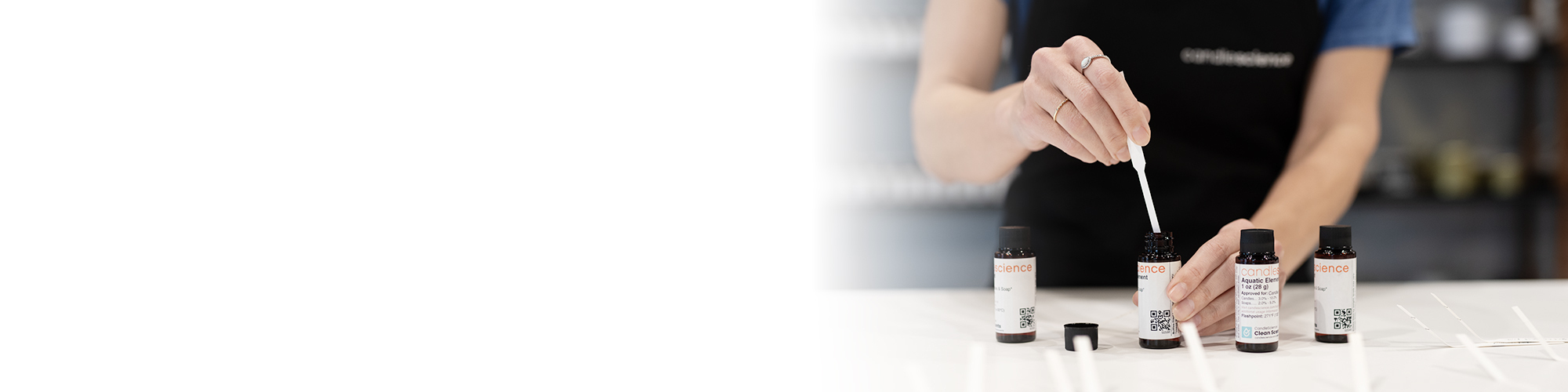 A whole pineapple, strawberries, and half a coconut on white marble pillars with a white candle in front of the pillars.