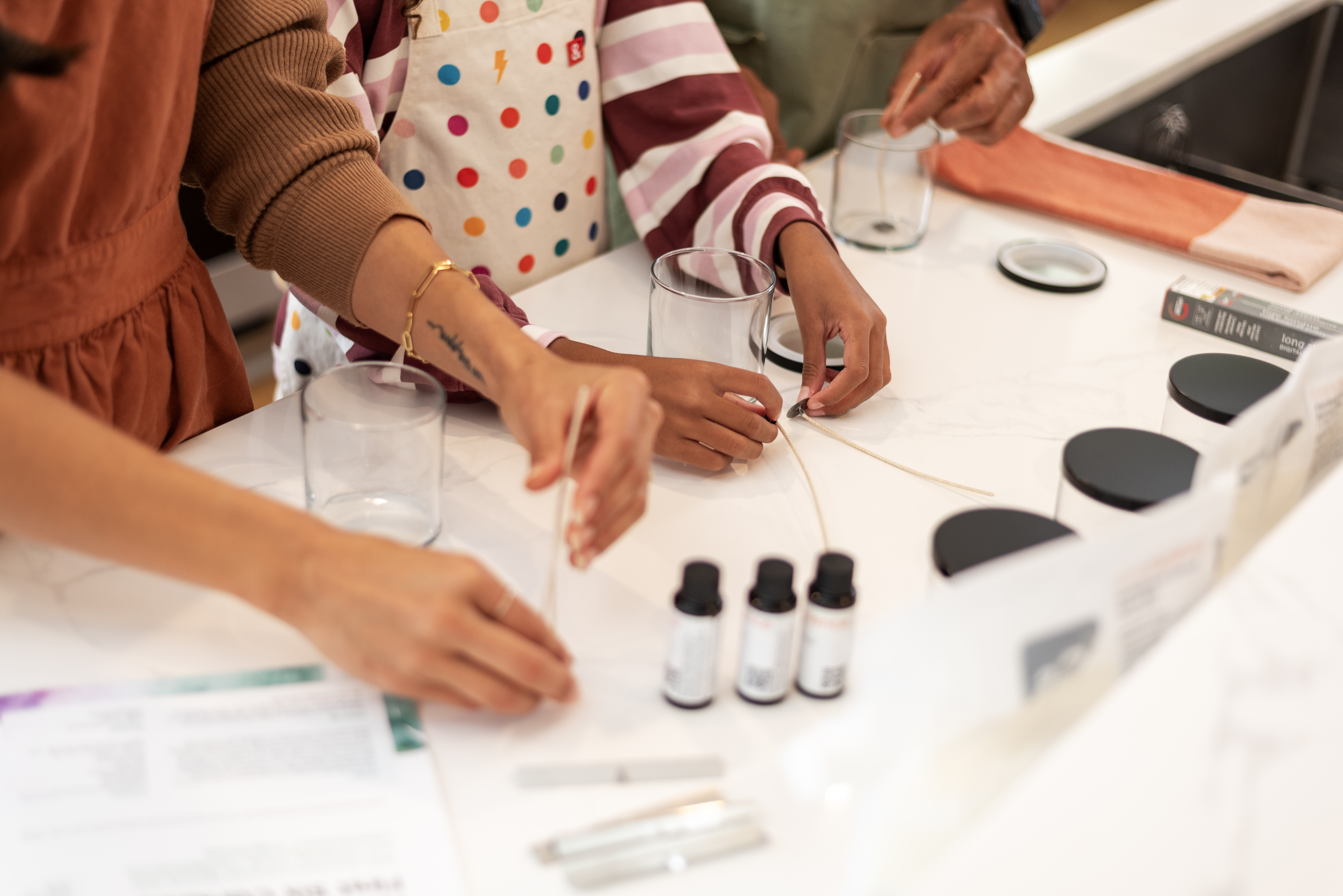 Candle making kits in brown boxes are stacked on a table in a living room setting