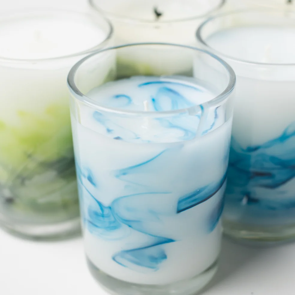 hot wax tinted green being poured into a container